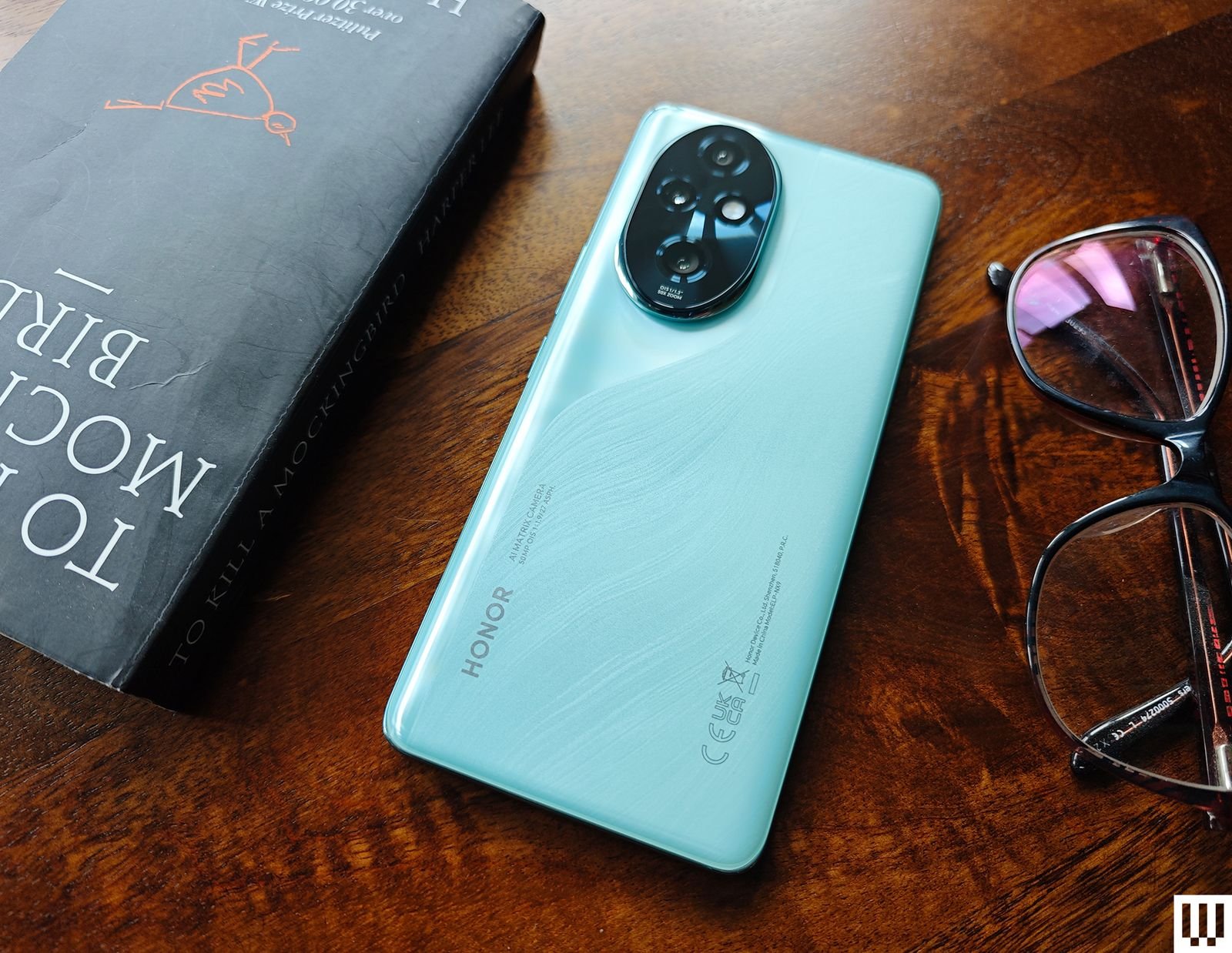 Teal mobile book and a pair of glasses on a wooden surface