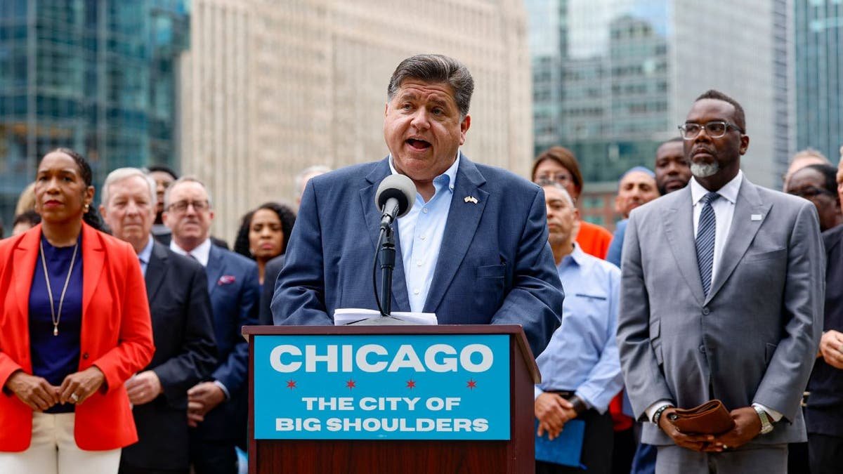 Illinois Governor JB Pritzker speaks at a press conference in the center of Chicago, surrounded by state and city leaders.
