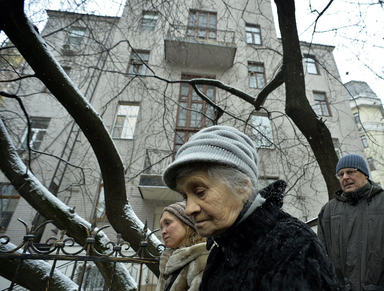 People who wear heads associated with winter clothes extend alongside naked branches and snow of a tree in front of a residential building in Moscow while attending a memorial composition ceremony for the victims of Soviet repression on the wall of their previous home.
