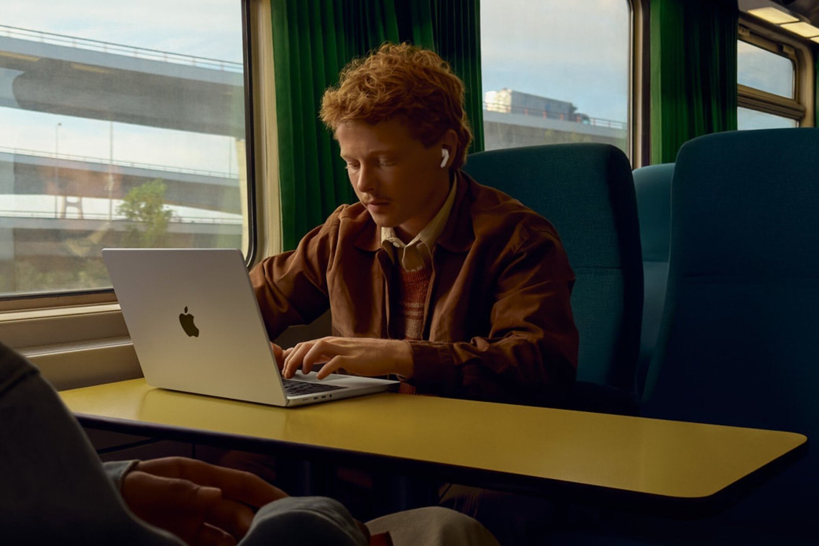 A person rides a train while wearing Apple AirPods 3.