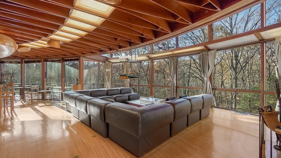 The house contains windows extending from floor to ceiling that provide views of the surrounding nature.