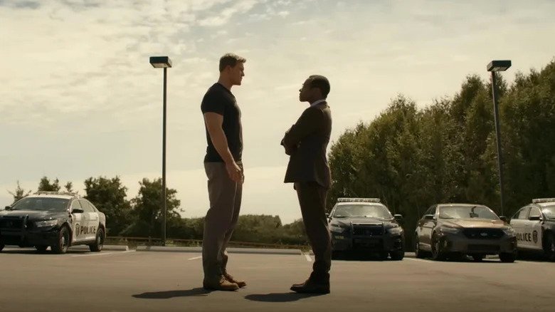 Jack Rich from Alan Richson stands in front of Oscar Judewa in Maldwin in a parking lot in a waiting yard in Reacher.webp