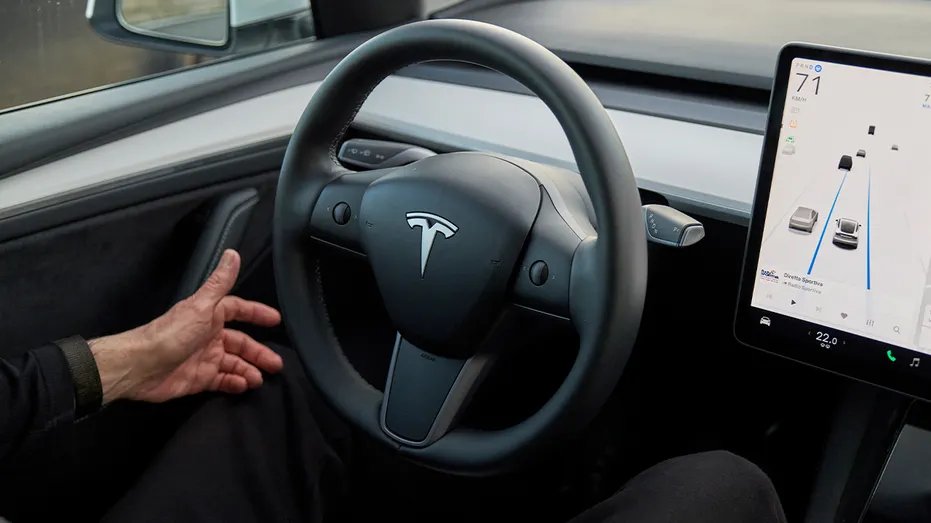 Man's hand near the steering wheel of a Tesla