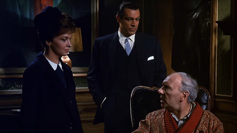Anthony Richmond, played by Sean Connery, stands behind Maria Marcello, played by Gina Lollobrigida, as she talks to Charles Richmond, played by Ralph Richardson, in Woman of Straw.