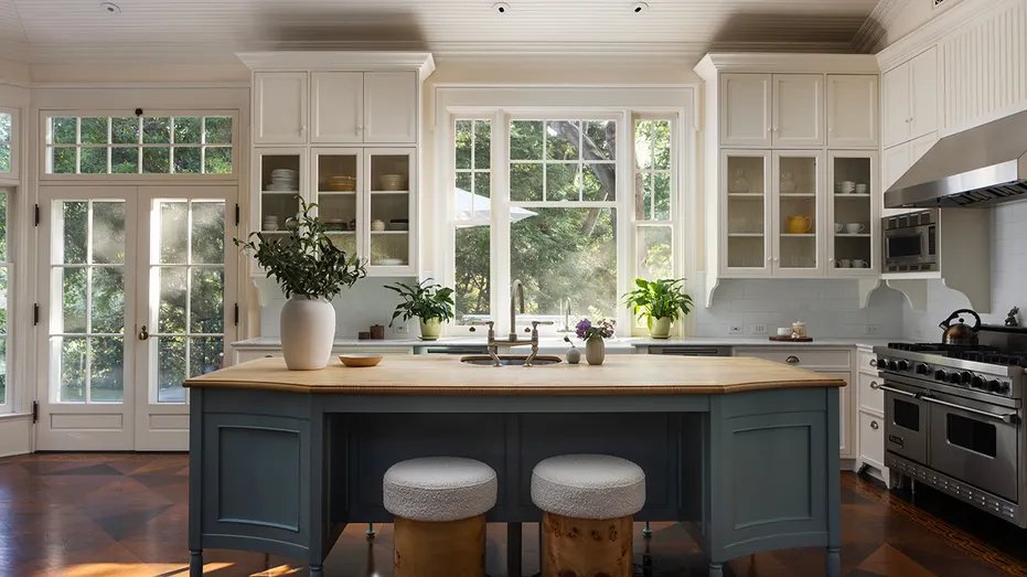 The kitchen has a center dining island and white cabinets.