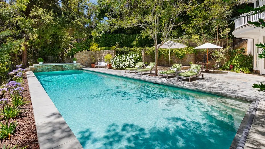 The backyard includes an outdoor dining area and a large swimming pool.
