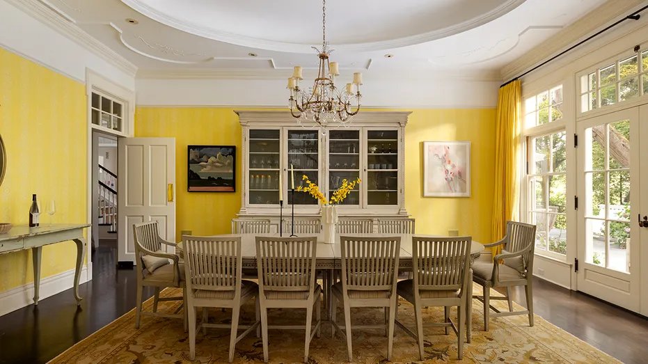 The dining room features yellow walls and a table large enough to seat 10 guests.