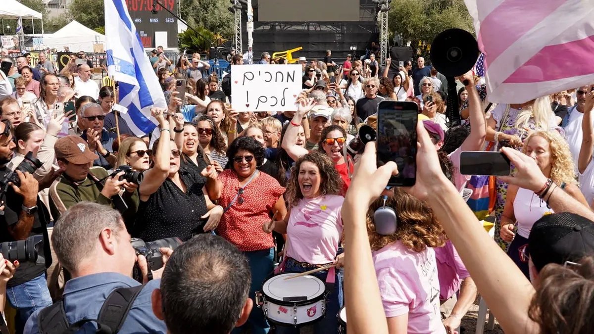 A crowd gathers in hostage square as people wave flags, take photos and play drums during a mass march.