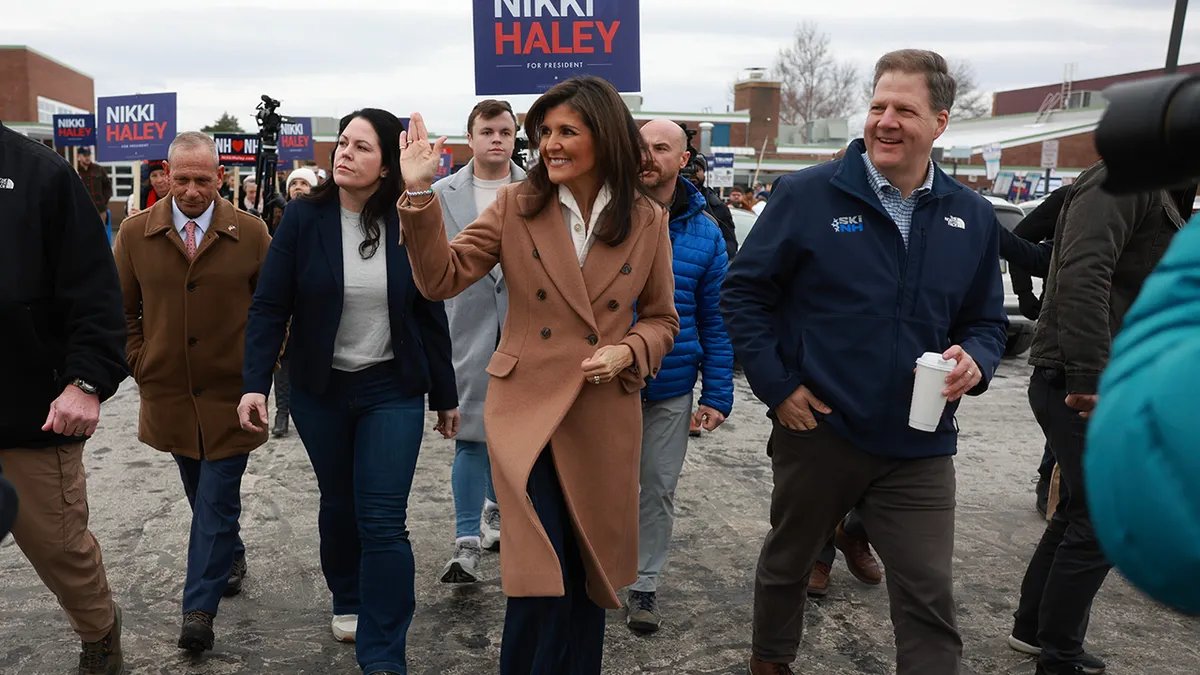 Nikki Haley waves and New Hampshire Governor Chris Sununu walks with other men and women by his supporters