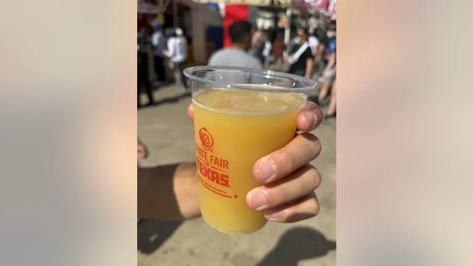 Mustard flavored beer in a plastic cup.
