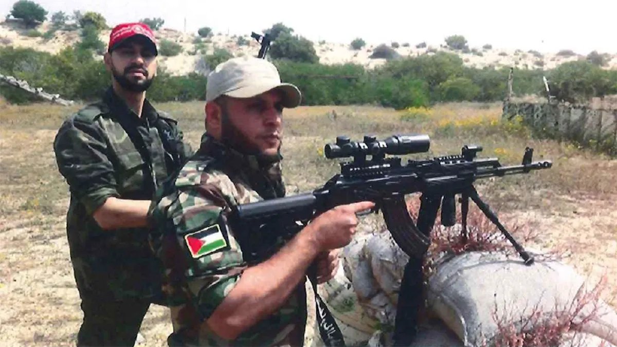 Mahmoud Amin Yaqoub Al-Muhtadi stands next to a man carrying a gun