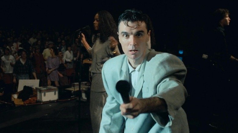 Stop the logic - David Byrne looks into the camera and raises the microphone