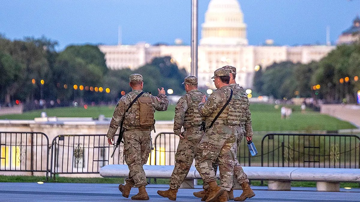Armed National Guard troops patrol with the US Capitol building in the background amid an increased security presence in Washington.