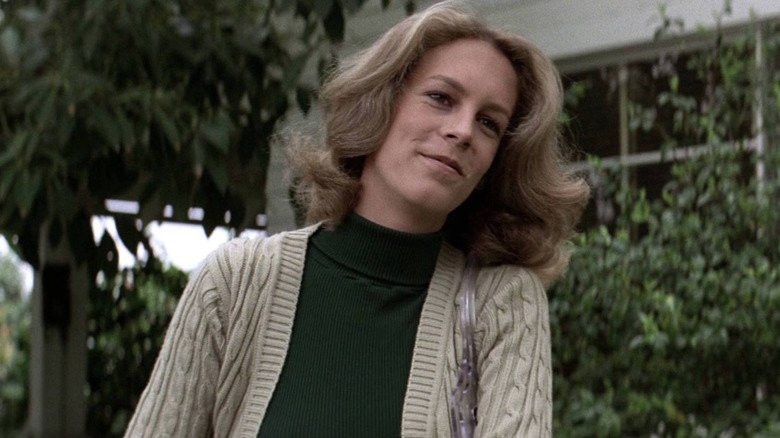 Laurie Strode smiling as she wears a green sweater and jacket on Halloween (1978)