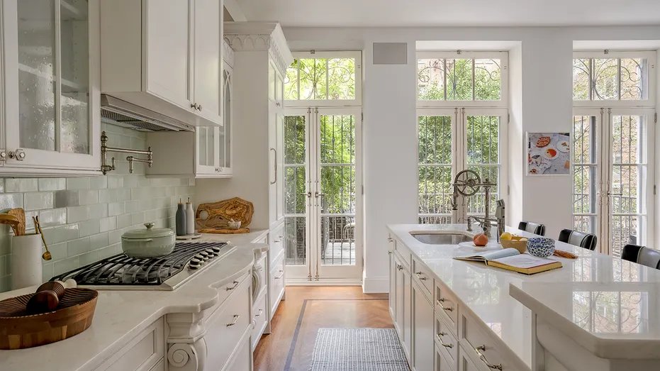 The kitchen features white cabinets and floor-to-ceiling glass windows.
