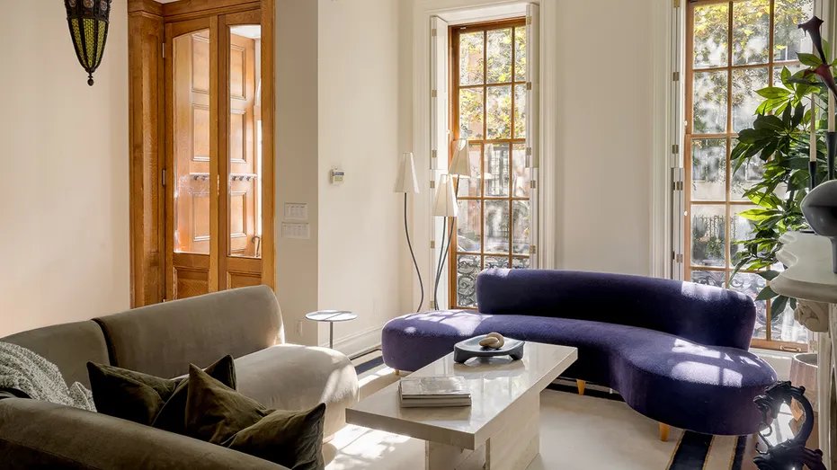A living room with sofas and green and purple windows looking outside.