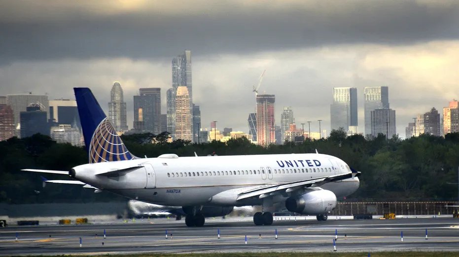 United Airlines plane on the airport runway during a cloudy day with the city in view