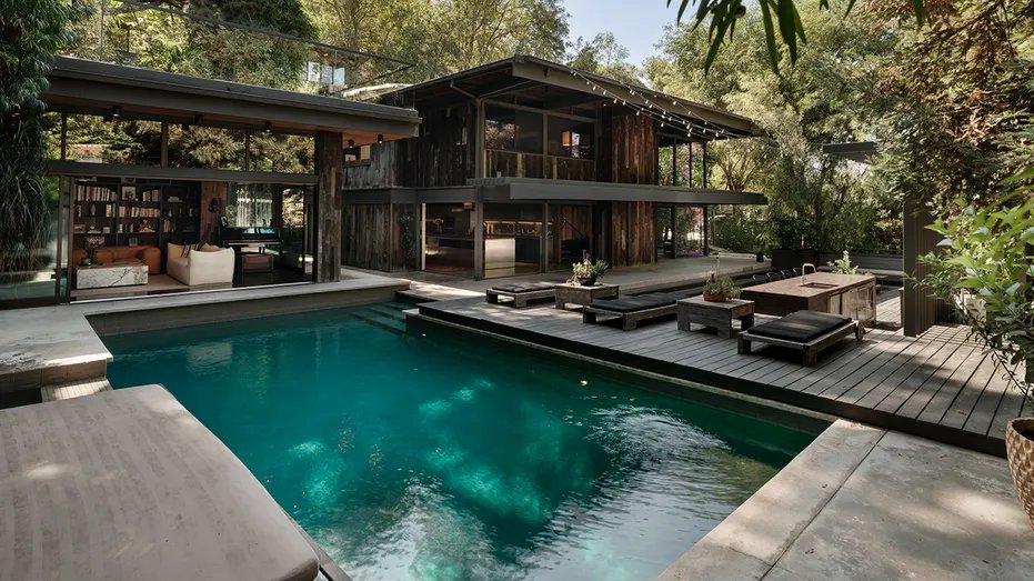 The house also has a large pool and seating areas in the backyard.