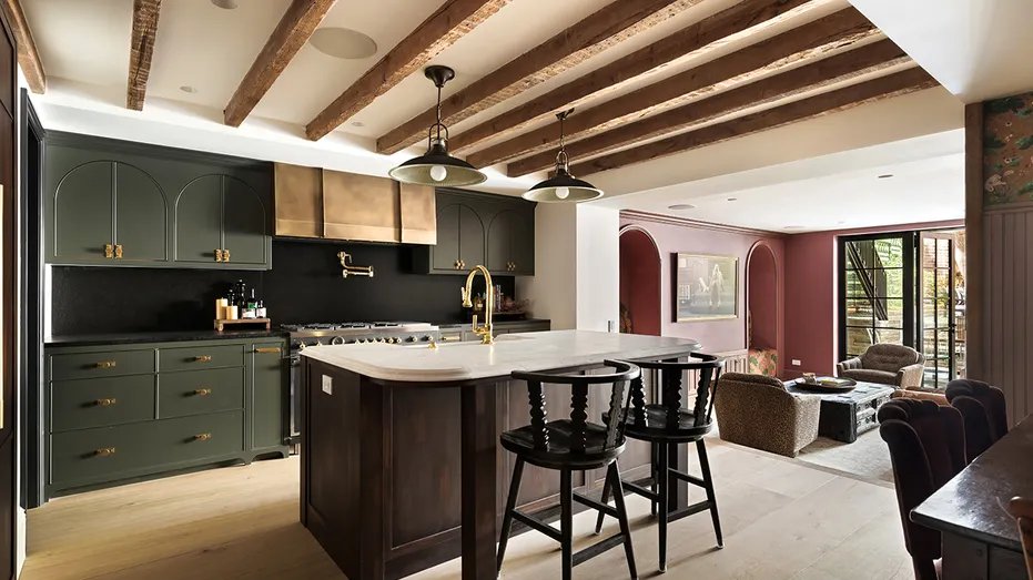 The kitchen features exposed wood beams on the ceiling, a center dining island and green cabinets.
