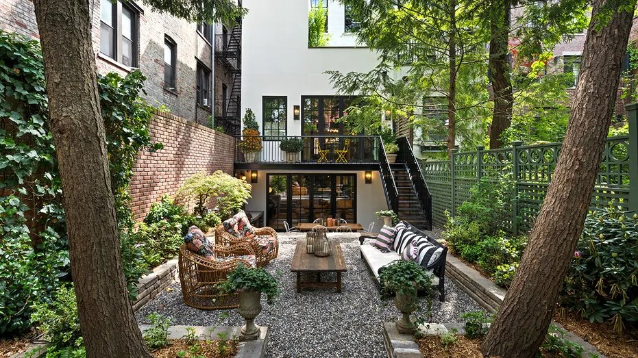 The backyard features green spaces, seating and dining areas.