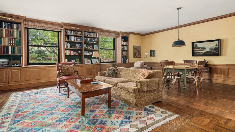 The house has a living room and informal dining area with built-in bookshelves and windows overlooking the gardens.