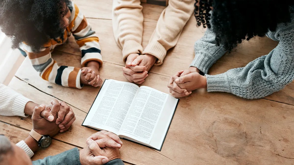 A family holding hands around the Bible