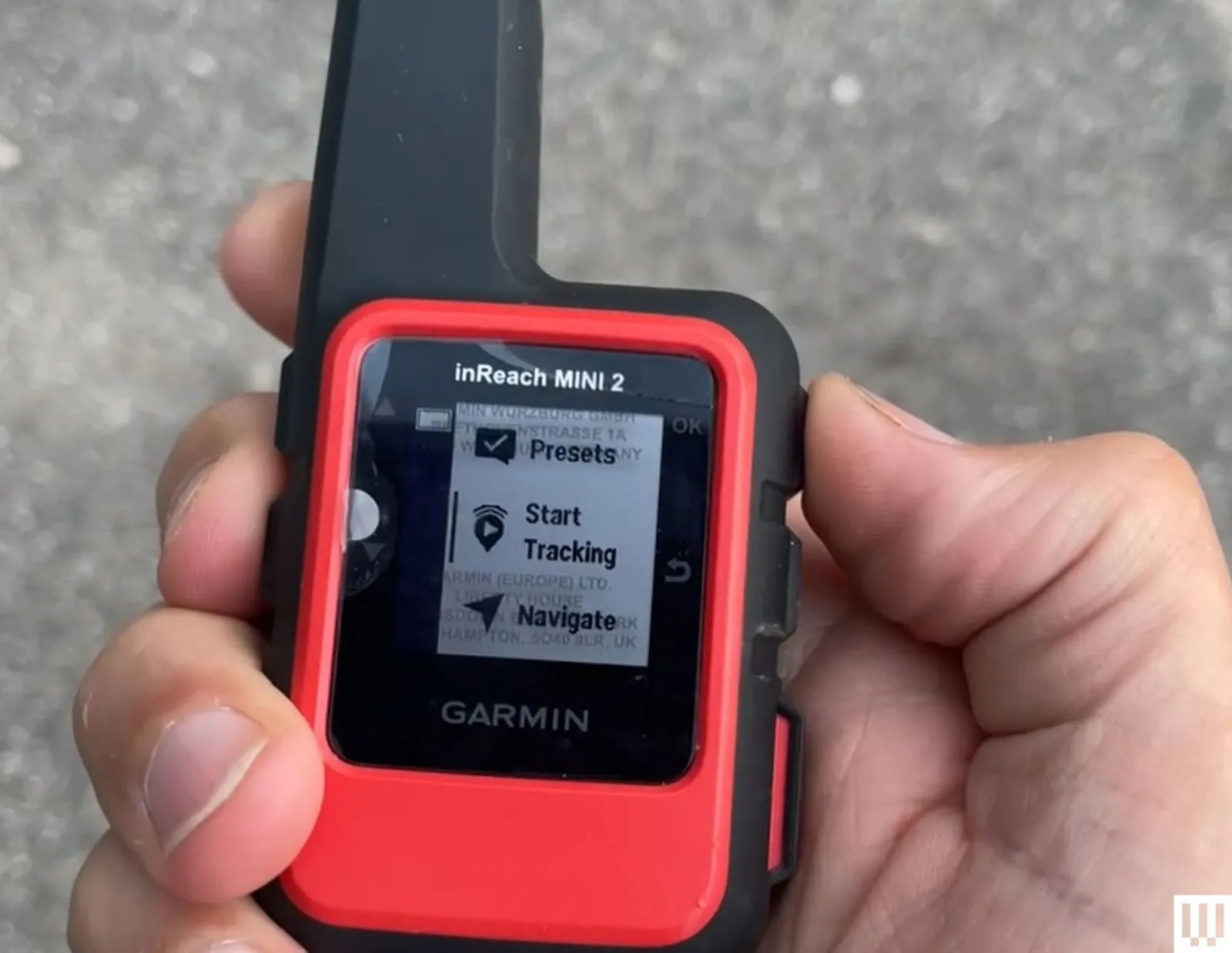 Hand holding small black and red device with a thick antenna and small screen