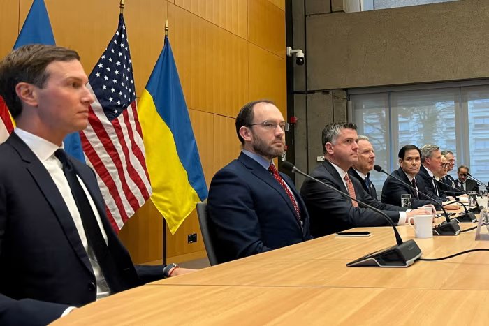 Jared Kushner, Steve Witkoff, Marco Rubio, and Daniel Driscoll sit at the conference table before the talks, with American and Ukrainian flags behind them.