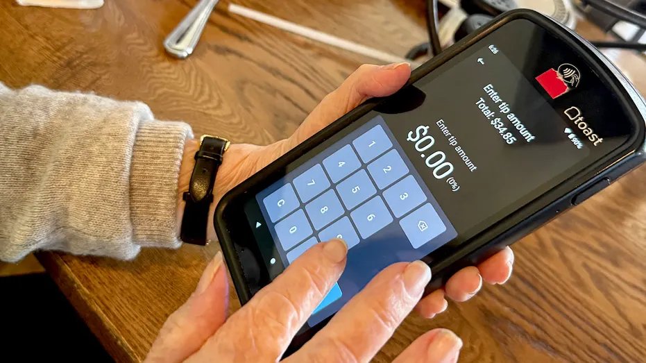 A woman enters a tip amount at a restaurant using a mobile tablet in Florida.