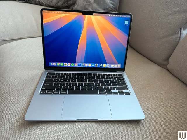 Front view of Apple MacBook Air 13-inch 2025 laptop open sitting on couch with screen showing desktop 