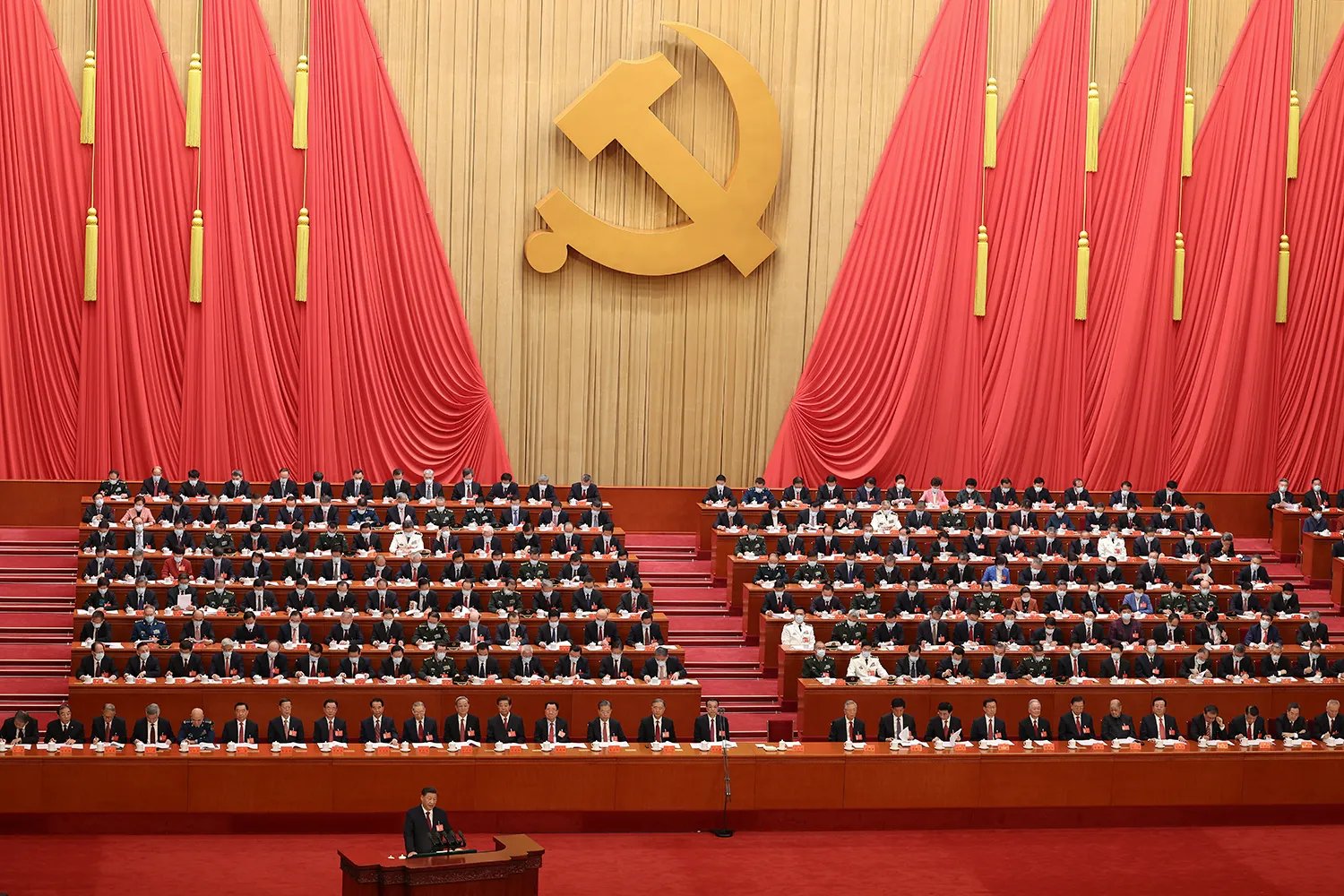 Xi Jinping is small in the foreground, speaking in front a room full of delegates.