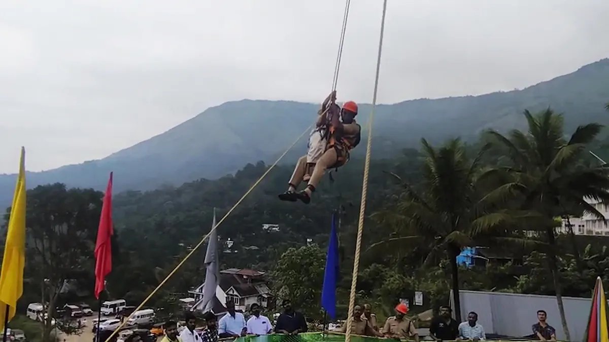 A firefighter saves a family from a sky-eating attraction by climbing a rope, while a crowd of people watches.