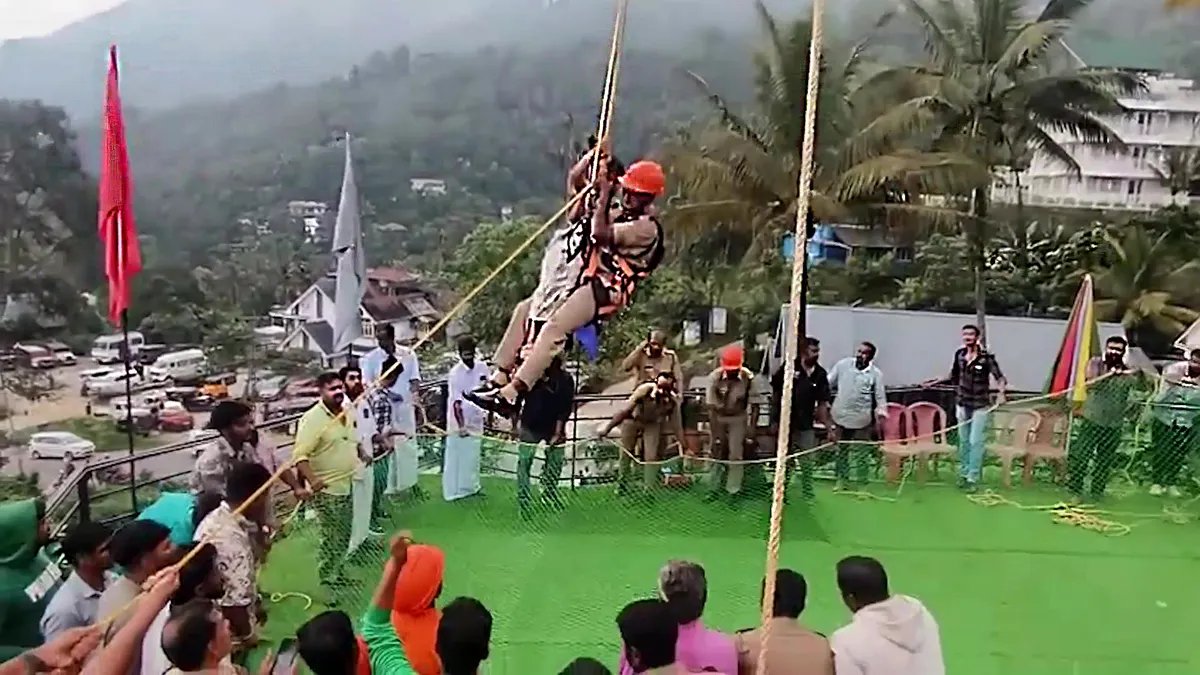 A firefighter saves a family by climbing a rope, while a crowd of people watches.