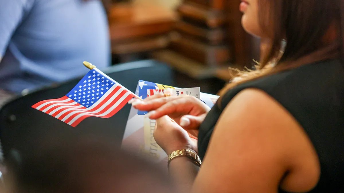An attendee at a US citizenship ceremony holds the flag on her lap