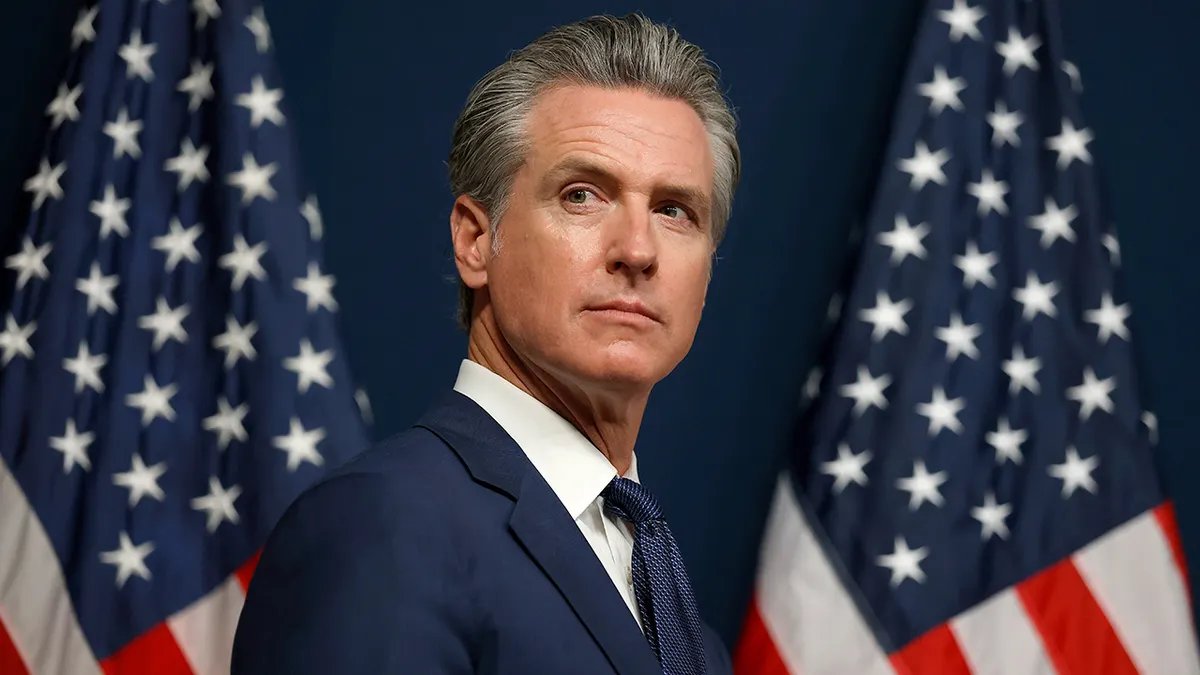 California Governor Gavin Newsom with two American flags in the background.