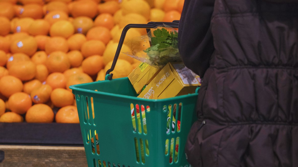 A shopper carries a grocery basket while purchasing food
