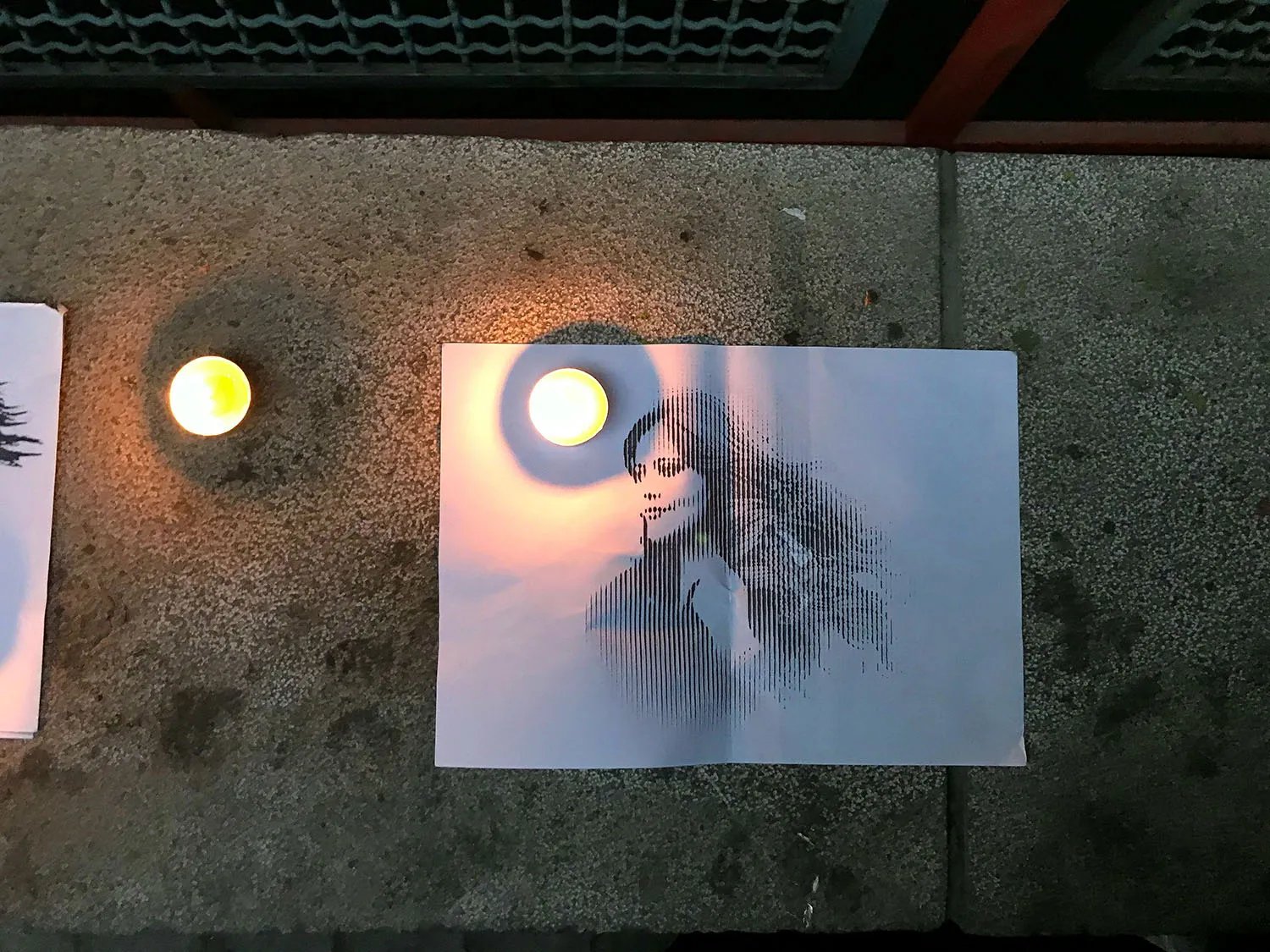A picture of a woman on the sidewalk with two small candles.