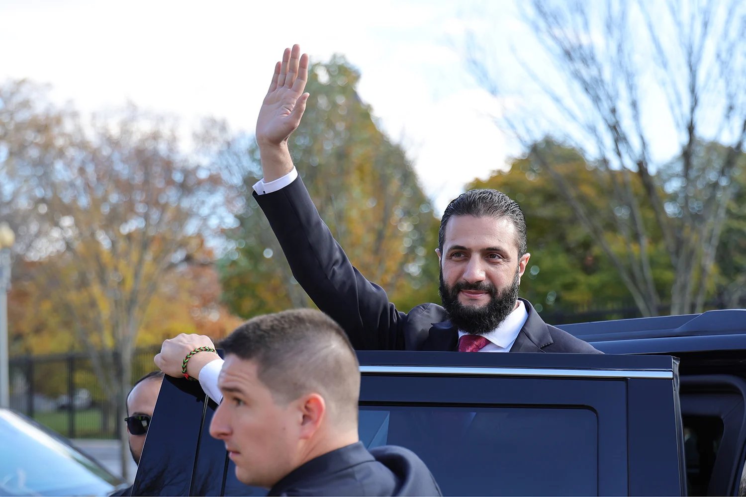 Syrian President Ahmed al-Sharaa waves as he gets in to a car.