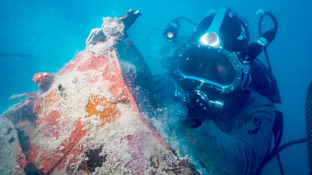 A diver examines the wreckage of a submerged World War II aircraft during an underwater recovery mission.