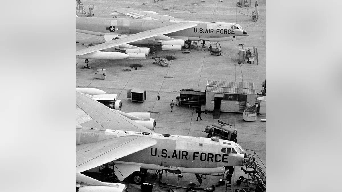 USAF B-52 bombers sit at a military airfield while ground crews work nearby.
