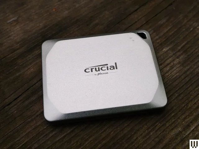 Silver square-shaped Crucial X9 external hard drive with angled corner edges sitting on dark wood surface