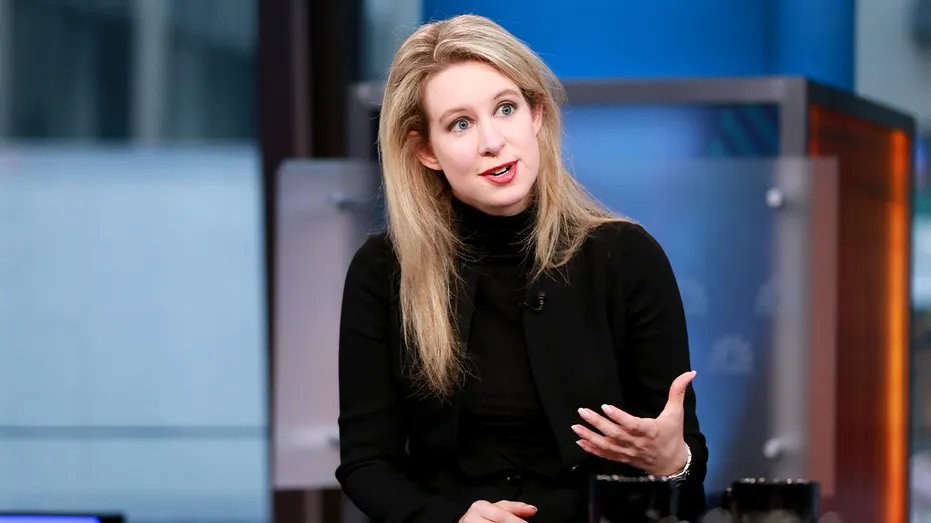 Elizabeth Holmes sits under studio lighting during a live broadcast of business news.