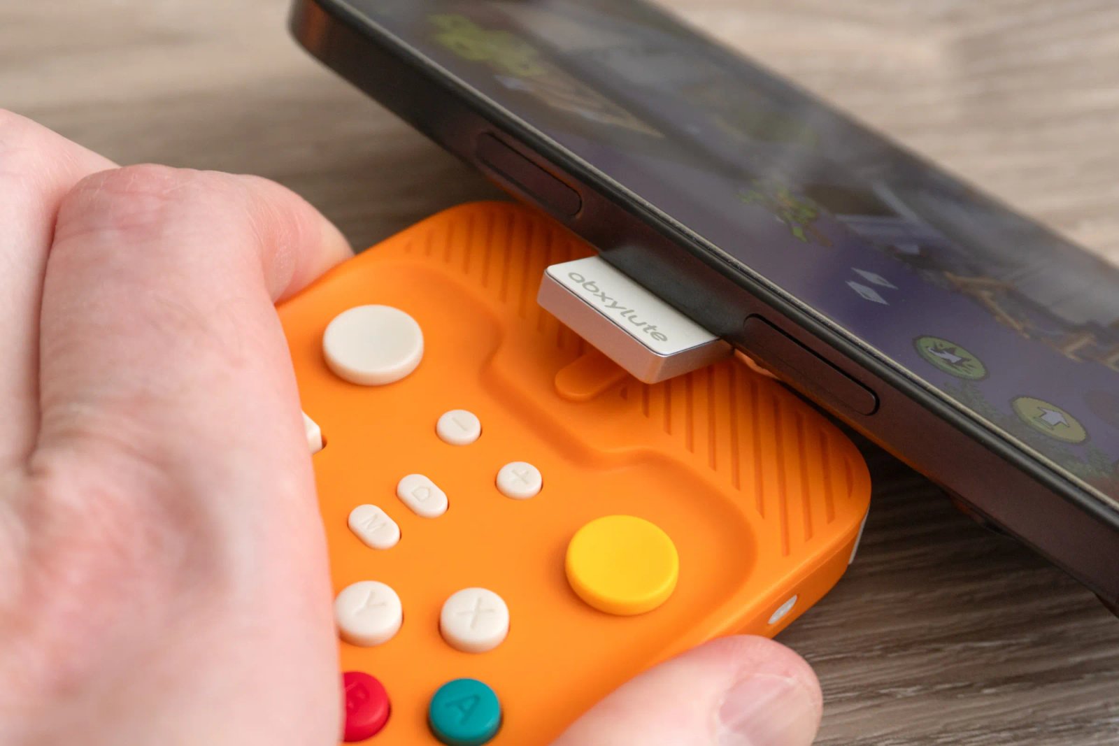 The magnetic holder for the Abxylute M4 is shown attached to an iPhone and separated from its controller.