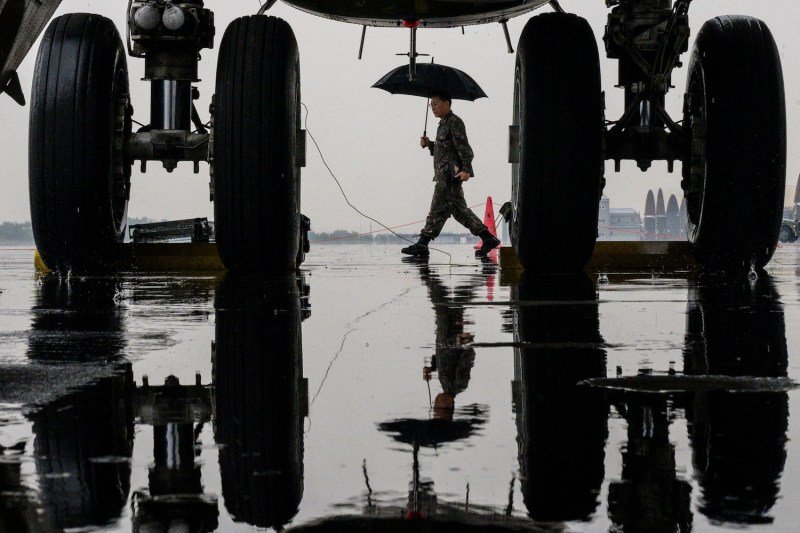 A soldier uses an umbrella to shield himself from the rain as he walks past the front wheels of a B-52H strategic bomber parked at a South Korean Air Force base at Cheongju International Airport on Oct. 19, 2023.