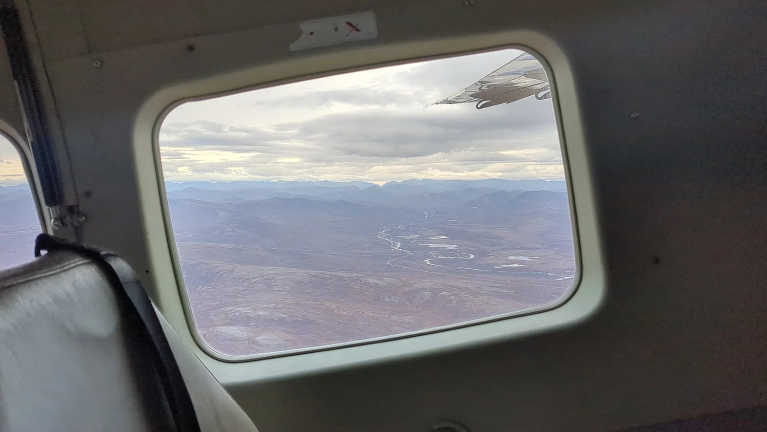 View of mountains, rivers and land from the window of a small plane.