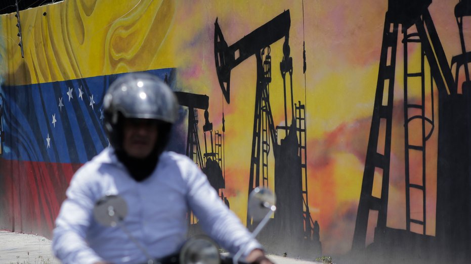 A man walks past a mural depicting the Venezuelan oil industry in Caracas, Venezuela.